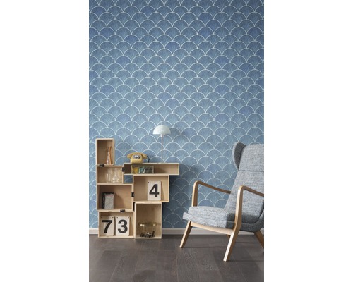 Raumansicht mit blauer Tapete mit Muschelmuster, Regalwürfel und Sessel