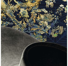 Detailansicht eines Raumes mit floral gemusterter Tapete und Teilansicht eines Sessels.