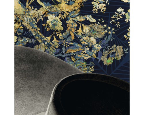 Detailansicht eines Raumes mit floral gemusterter Tapete und Teilansicht eines Sessels.