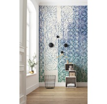 Zimmer mit floral gemusterter Tapete, schwarzem Drahtkorb und weißem Regal.