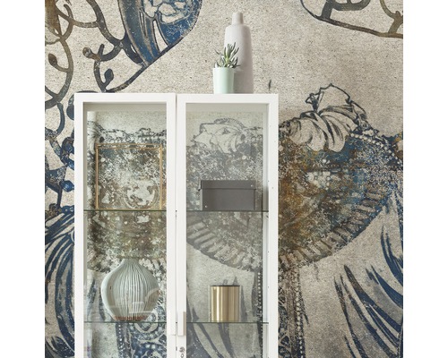 Dekoratives Wohnzimmer mit einem weißen Glasschrank vor einer gemusterten Tapete.