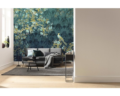 Wohnzimmer mit Sofa vor einer gemusterten Tapete mit Pflanzen- und Vogelmotiven