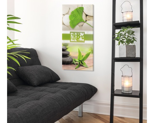 Dekorative Wandkunst mit Steinmotiv und Pflanzenmotiven in einem hellen Raum mit Sofa und Regal