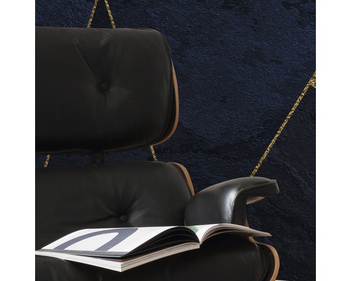 Detailansicht eines Sessels mit Zeitschrift vor einer Wand mit geometrischem Muster