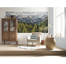 Wohnzimmer mit Holzschrank, Sessel, Beistelltisch und Fototapete mit Bergmotiv