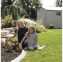 Mutter und Tochter ernten Gemüse im Garten mit Gartenhaus