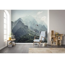 Wohnzimmer mit Bergmotiv-Tapete, Sessel und Regalen