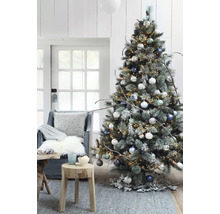 Dekorierter Weihnachtsbaum mit Lichtern, Christbaumkugeln und rustikalen Dekorationen in einem Wohnzimmer.