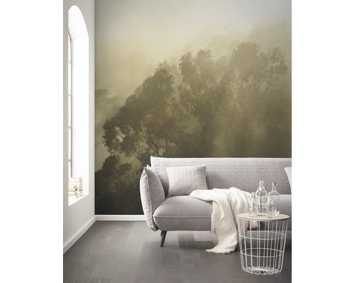 Wohnzimmer mit Fototapete eines Waldes im Nebel, Sofa und Beistelltisch.