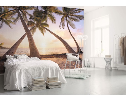 Helles Schlafzimmer mit Fototapete, die einen Strand mit Palmen darstellt.