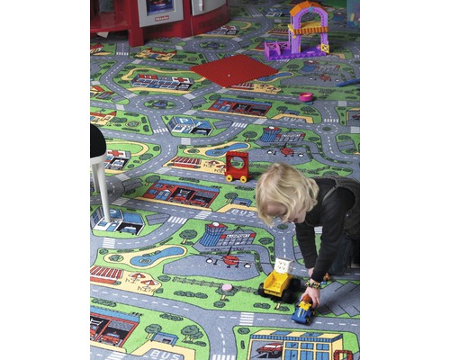 Kind spielt mit Spielzeugautos auf einem Teppich mit Stadtmotiv
