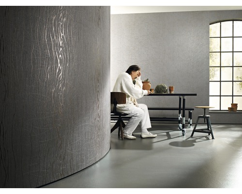 Helles Zimmer mit grauer Design Tapete und sitzender Person am Tisch