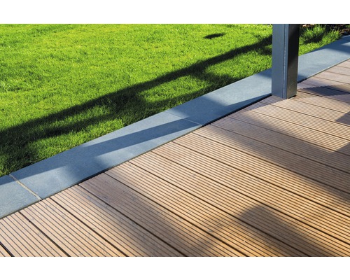 Nahaufnahme einer Holzterrasse neben Rasenfläche und einer Einfassung