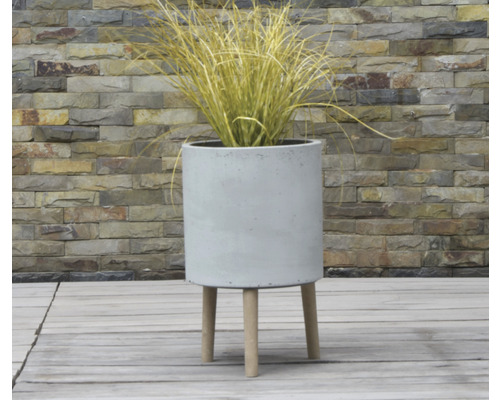 Zylindrischer Pflanzkübel aus Beton mit Holzfüßen und Ziergras