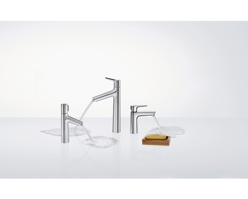 Drei Wasserhähne unterschiedlicher Größe und ein Stück Seife auf einer Ablage.