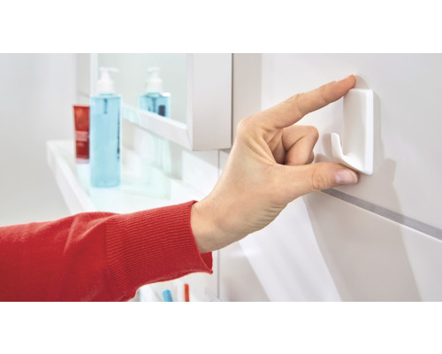 Hand befestigt selbstklebenden Haken an Badezimmerwand