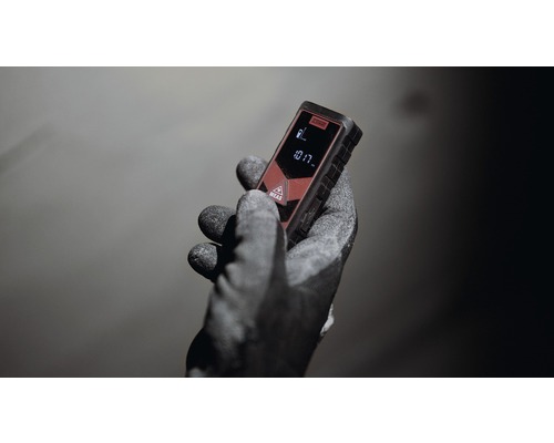 Eine Hand mit Arbeitshandschuh hält einen Laser-Entfernungsmesser.