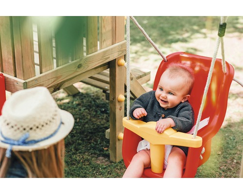 Ein Baby sitzt in einer Schaukel auf einem Spielplatz.