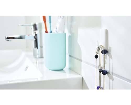 Helles Badezimmer mit Waschbecken, Zahnputzbecher und Wandhaken mit Halskette