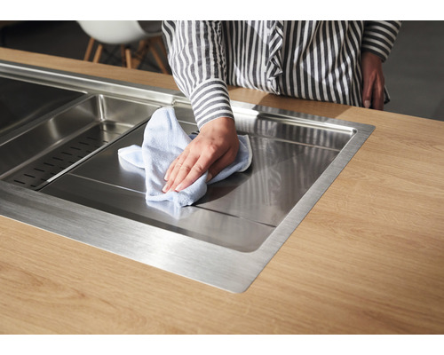 Edelstahlspüle auf Arbeitsplatte wird mit einem Tuch gereinigt