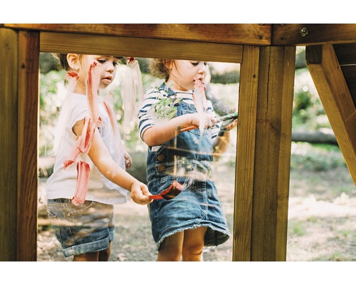 Zwei Kinder bemalen die Scheibe eines Spielhauses mit Farbe.