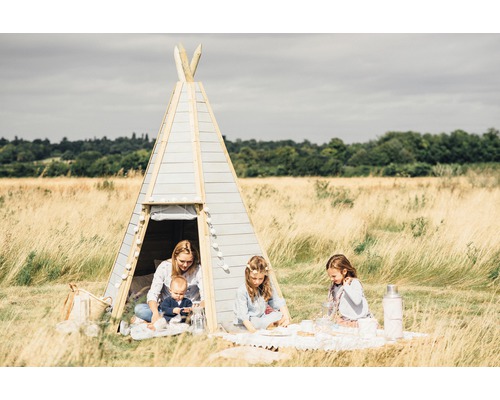 Szene im Freien mit einem Kinderspielzelt, einer Mutter mit einem Baby und zwei Mädchen, die ein Picknick machen