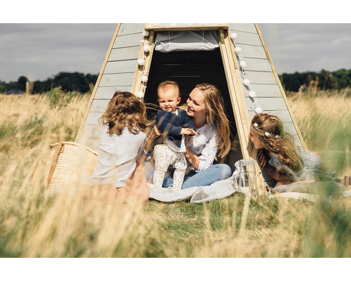 Familie entspannt vor einem Spielzelt im Freien