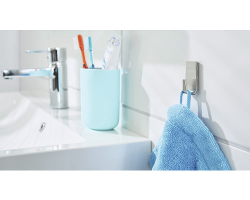 Helles Badezimmer mit Waschbecken, Zahnputzbecher, Handtuchhaken und blauem Handtuch