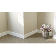 Raumecke mit weißen Sockelleisten auf Holzboden und Blumenarrangement.