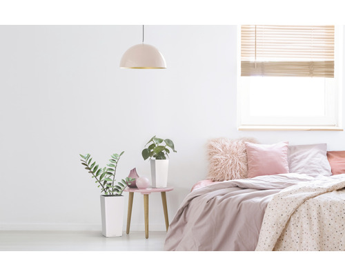 Helles Schlafzimmer mit Bett, Nachttisch, Lampe und Pflanzen