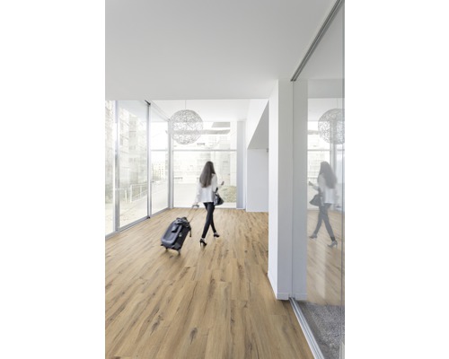 Heller Raum mit Laminatboden und einer Frau mit Rollkoffer