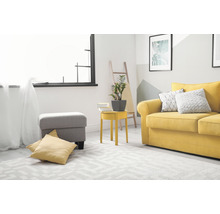Wohnzimmer mit gelbem Sofa, grauem Hocker und geometrischem Teppich