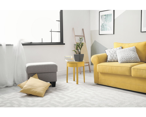 Wohnzimmer mit gelbem Sofa, grauem Hocker und geometrischem Teppich