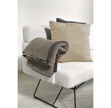 Beige Decke und Kissen auf einem hellen Sofa