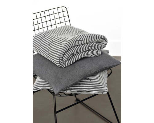 Gefaltete Decke und Kissen mit Streifenmuster auf einem Stuhl