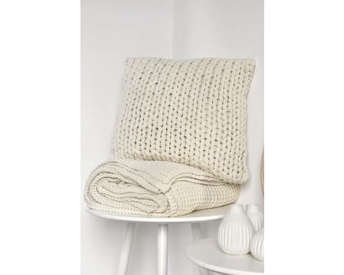 Gestricktes Kissen und Decke auf einem Tisch