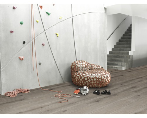 Raumansicht mit Kletterwand, Sessellandschaft, Kletterausrüstung und Treppe.