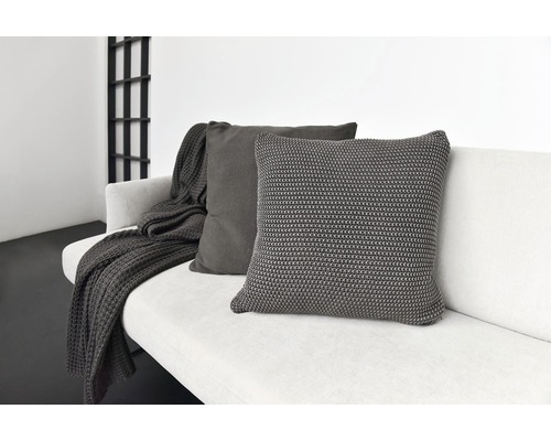 Zwei graue Kissen und eine Decke auf einem Sofa