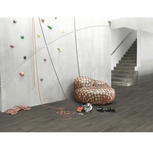 Szene mit Kletterwand, Seil, Kletterschuhen und Sessel im Raum