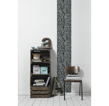 Raumgestaltung mit Holzkistenregal, Dekorationselementen und einer Wandtapete mit Schriftmotiven
