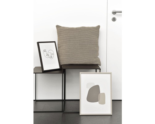 Dekorative Szene mit einem Kissen, zwei Tischen und zwei gerahmten Kunstdrucken