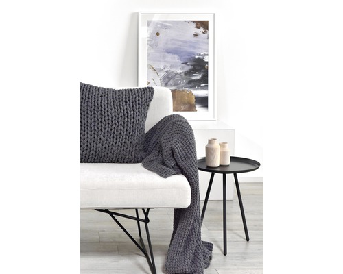 Dekoratives Wohnzimmer mit weißem Sofa, grauem Strickkissen, Wolldecke und kleinem Beistelltisch