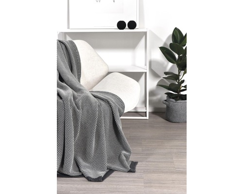 Wohnszene mit Sessel, Decke, Regal und Zimmerpflanze