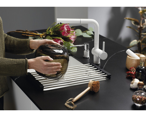 Frau wäscht Glasvase in einer Spüle mit Abtropfgestell und Armatur