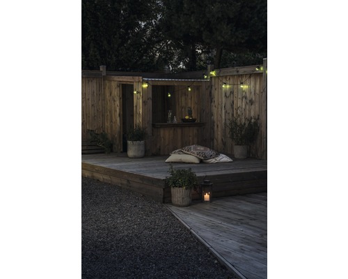 Holzterrasse mit Sitzgelegenheit, Pflanzen und Lichterketten im Garten