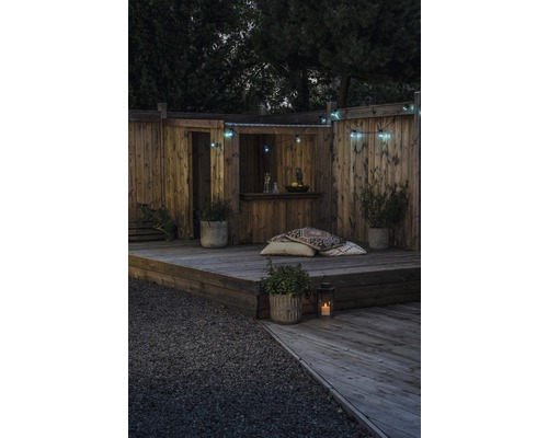 Holzterrasse mit Bar, dekorativer Beleuchtung und Pflanzgefäßen für eine gemütliche Gartengestaltung.