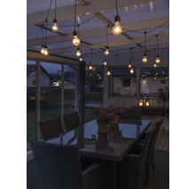 Terrasse mit Tisch, Stühlen und Lichterkette für eine stimmungsvolle Atmosphäre.
