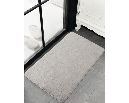 Rechteckige Badematte vor einer Tür mit zwei Hausschuhen