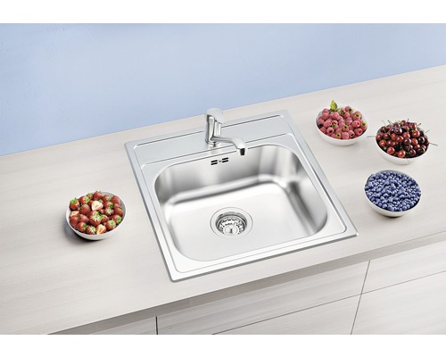 Edelstahlspüle mit Armatur und Schalen mit Früchten auf einer Küchentheke