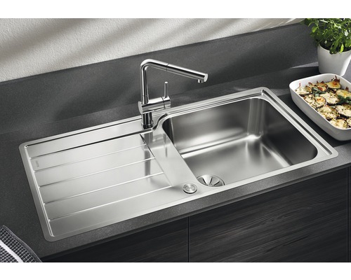 Edelstahlspüle mit Abtropffläche und Wasserhahn auf einer Arbeitsplatte